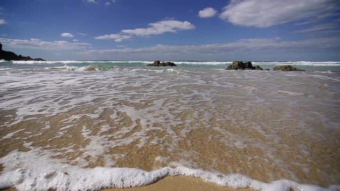 泡沫状的小波浪冲上沙滩