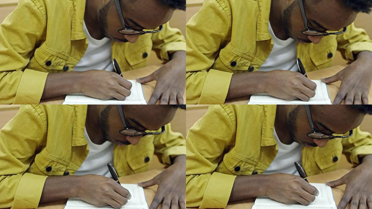 黑人俯身在笔记本上写作