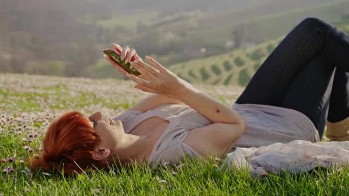 DS女人在草地上使用智能手机