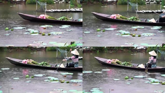越南女子在越南同塔省Thap Muoi的大湖中下雨时，用粉红色的莲花和莲花吊舱划着传统的木船的4k镜