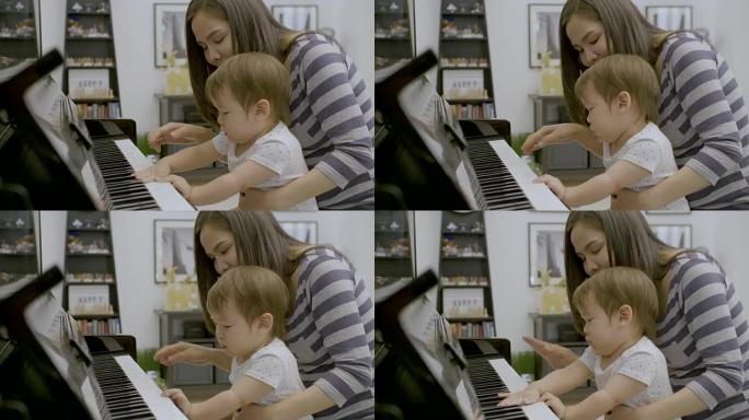 年轻的亚洲母亲和她的男婴弹钢琴