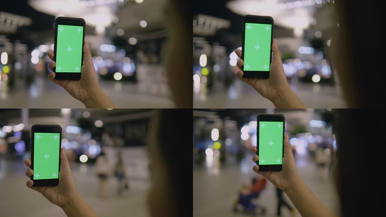 女人在街上使用带有绿屏的智能手机