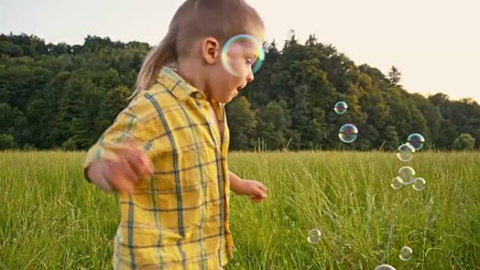 SLO MO男孩在草地上捕捉泡沫