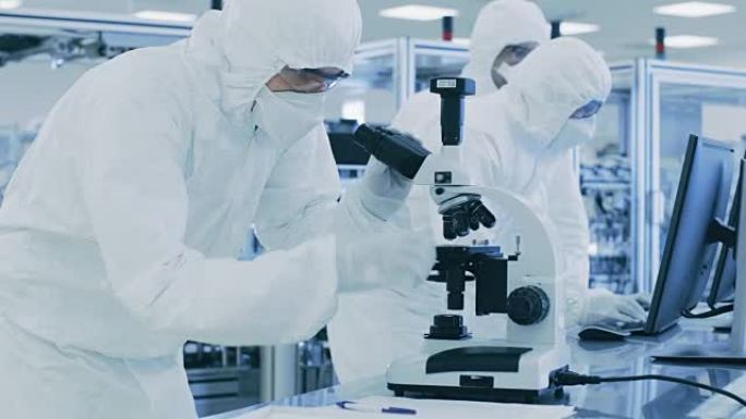 在实验室里，科学家穿着防护服做研究，用显微镜写下数据。在生产半导体和药品的现代工厂工作的工人。