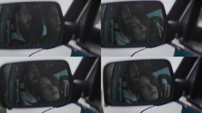 一对年轻夫妇坐在一辆车里，拥抱着，看着前面的窗户