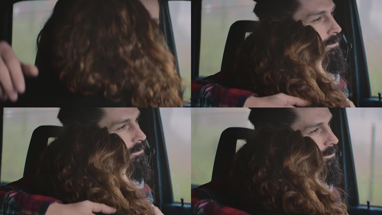 年轻夫妇坐在车里，拥抱着，透过前窗望去