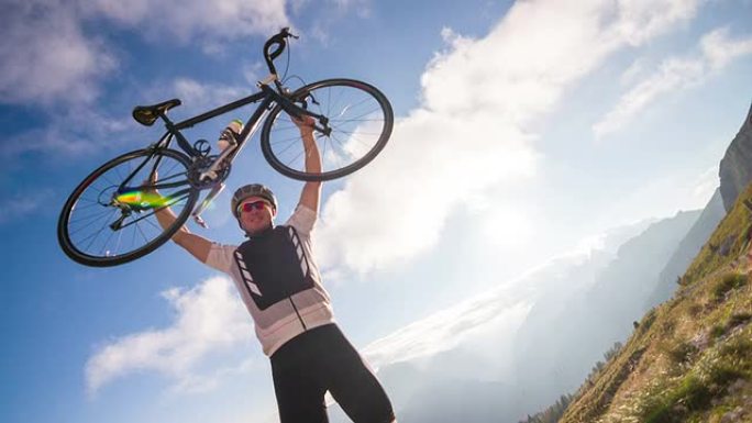 年轻的男自行车手在山顶成功举起自行车