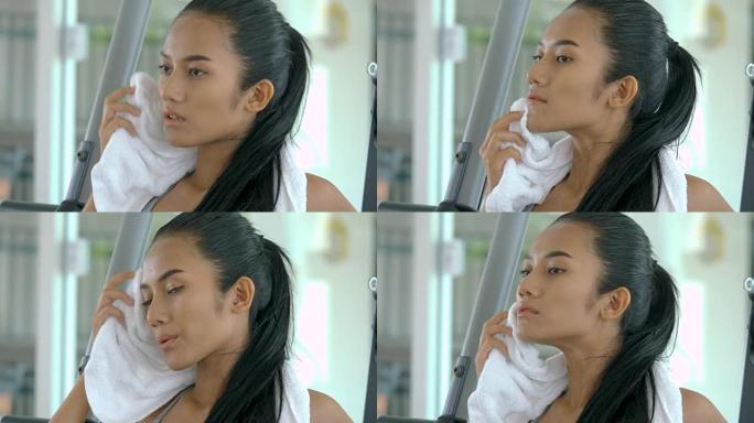 年轻的亚洲女运动员在健身房擦汗。艰苦锻炼后休息