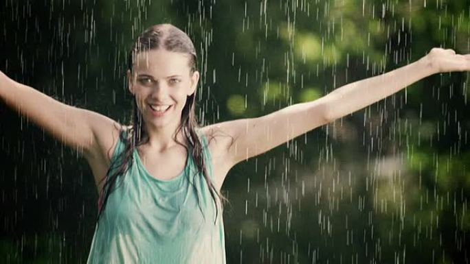 女人在夏雨中享受并伸展她的手臂