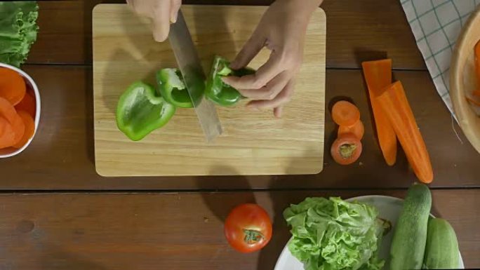 女酋长在厨房的切菜板上制作沙拉健康食品和切碎甜椒的俯视图。