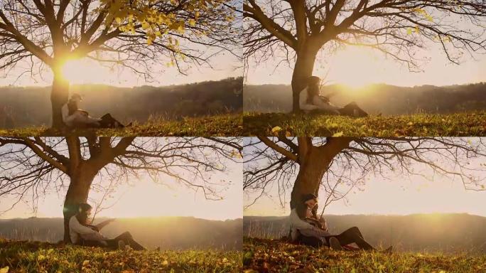 日落时坐在树下的情侣