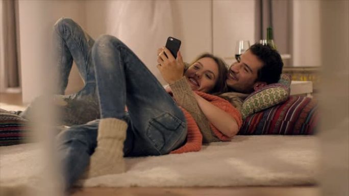 情侣在地毯上用智能手机看照片