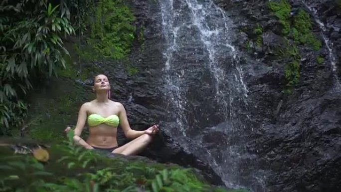 在瀑布旁沉思的女人。热带雨林。假日放松