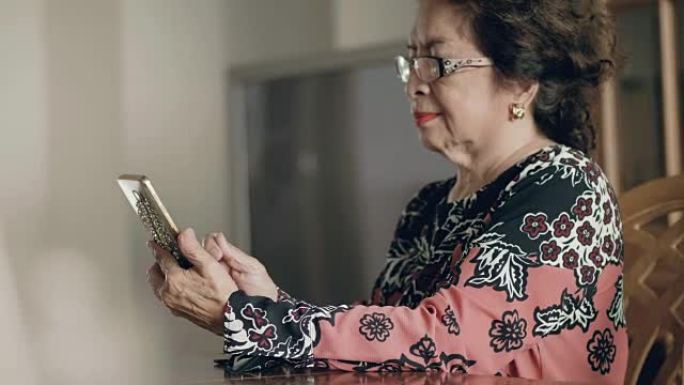 亚洲高级女性在家中客厅使用智能手机。