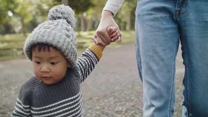 母亲与婴儿牵手在木头中行走