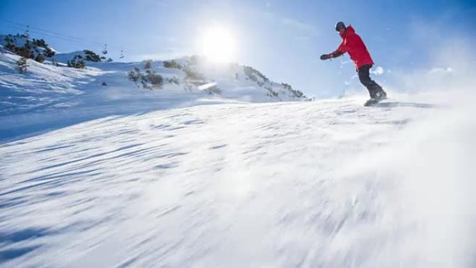 在阳光明媚的日子里，滑雪者沿着滑雪坡骑行，向他喷雪