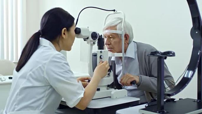 女眼科医生检查高级男子的眼睛