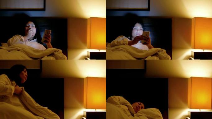 女人在睡觉前关掉灯前使用智能手机和困倦