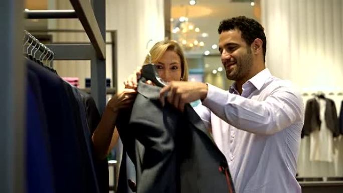 英俊的男人在男装店试穿他的伴侣给他的西装