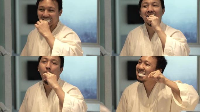 4k特写镜头亚洲男子早上在豪华酒店卧室，生活方式和休闲概念醒来时，在镜子前的浴室用牙刷刷牙