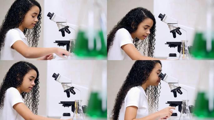 聪明的中学女生在化学实验室期间使用显微镜