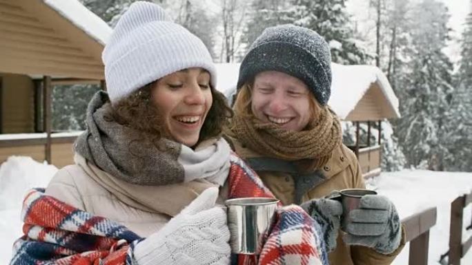 在冬季森林里，笑着的夫妇在户外喝茶