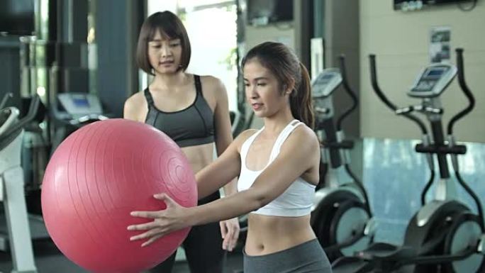 与私人教练一起使用健身球进行伸展运动的妇女