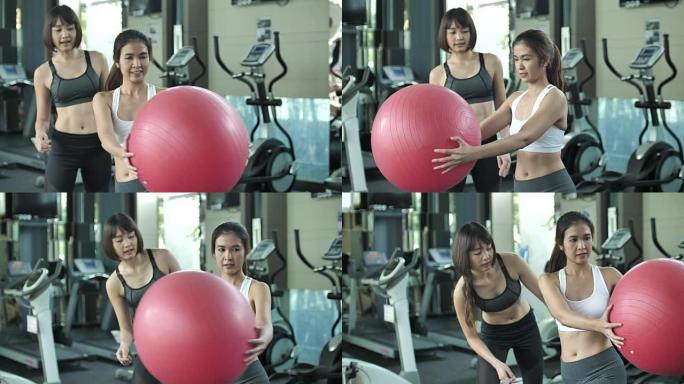 与私人教练一起使用健身球进行伸展运动的妇女