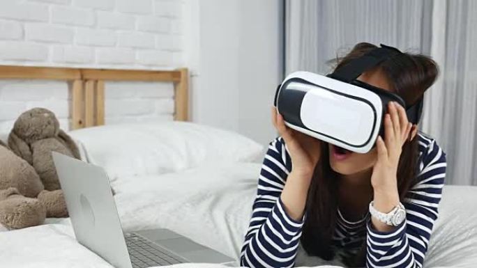 年轻女子在家里的床上戴着虚拟现实耳机