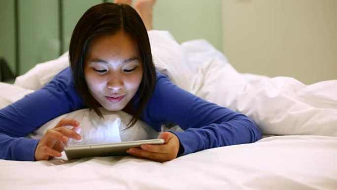 在床单上使用数字平板电脑的美女