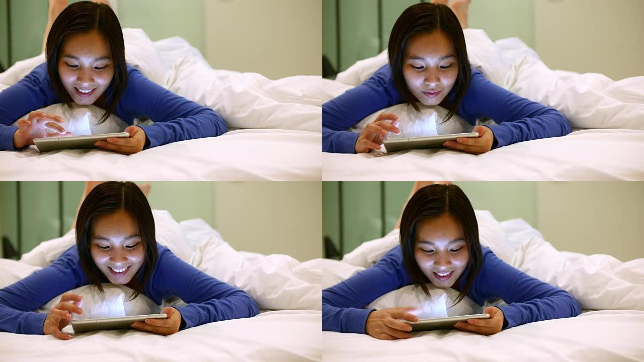 在床单上使用数字平板电脑的美女