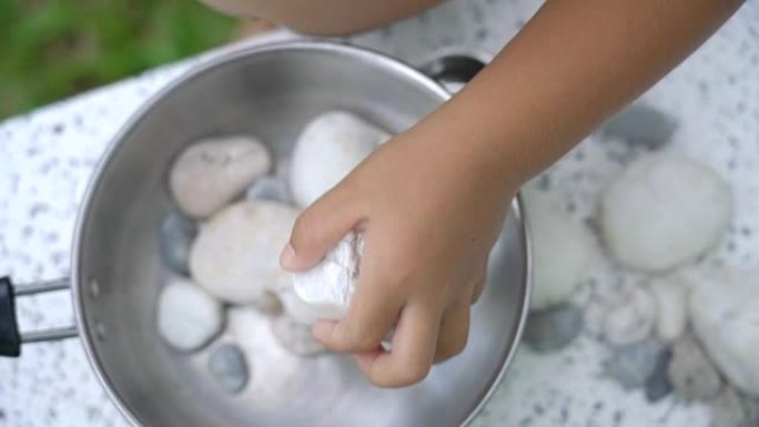 SLO MO幼儿玩石头做饭。