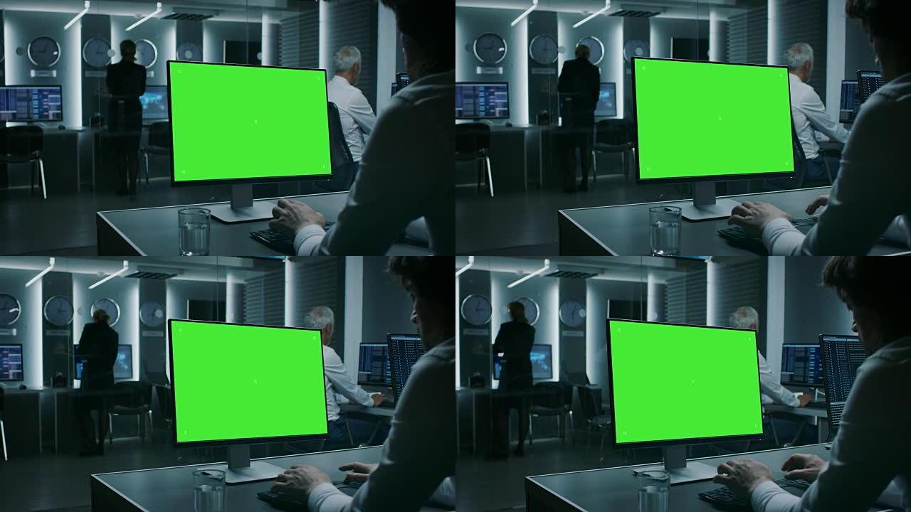 在金融业务运营中心的绿色模拟屏幕计算机上工作的商人的后视图镜头。