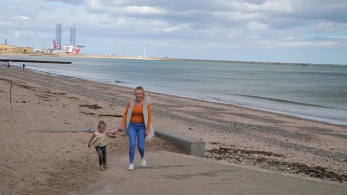 母女在海滩旁散步牵手