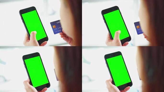 女人用信用卡，绿屏在智能手机上购物