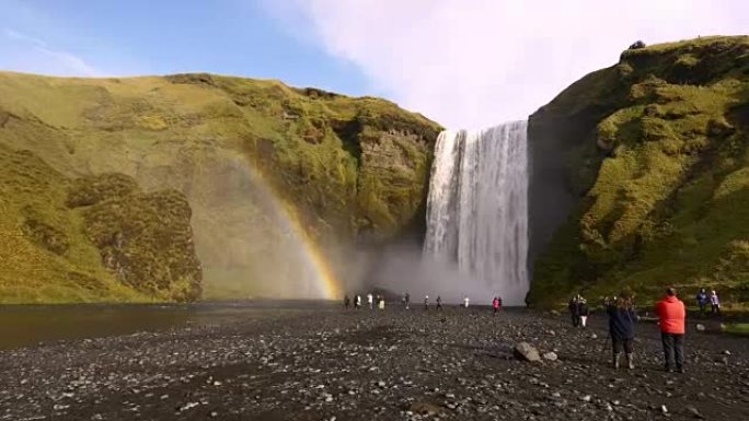 游客在冰岛欣赏Skogafoss瀑布的景色