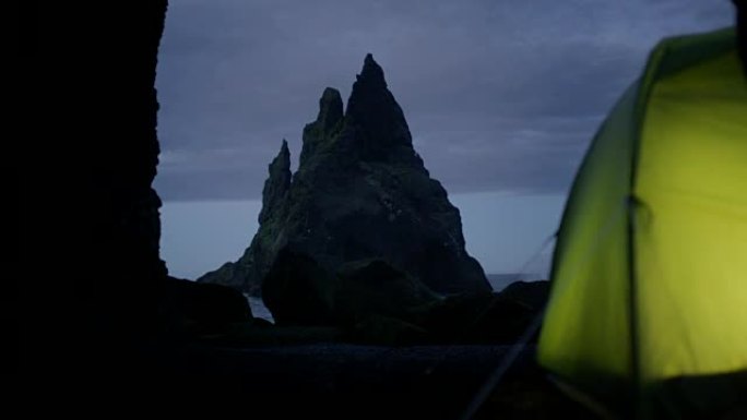 野生岩石海滩上的绿色帐篷。