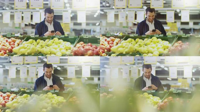 在超市: 男人站在新鲜农产品区附近选择水果时使用智能手机。大光明正宗商店。
