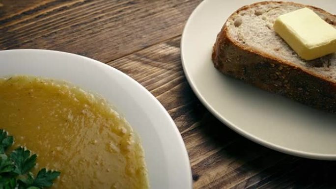 一碗汤和面包放在木桌上