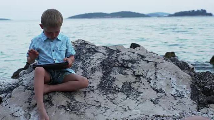 坐在岩石岸边的男孩。