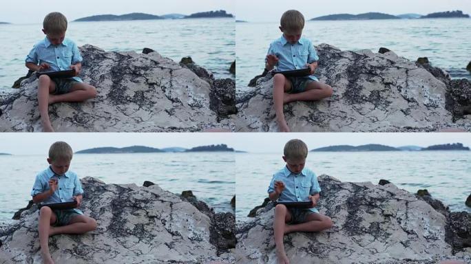 坐在岩石岸边的男孩。