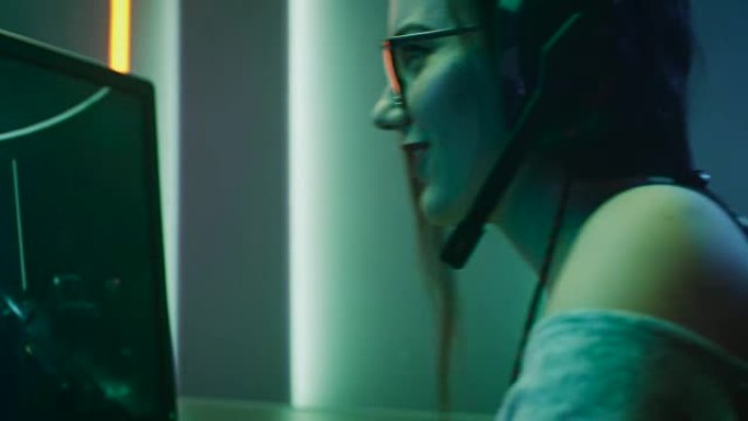 美丽的职业玩家女孩在她的个人电脑上玩第一人称射击在线视频游戏的弧光。休闲可爱的极客戴着眼镜，对着耳机