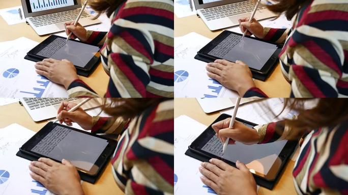 在数字平板电脑显示屏上使用数字笔书写笔记的女商人
