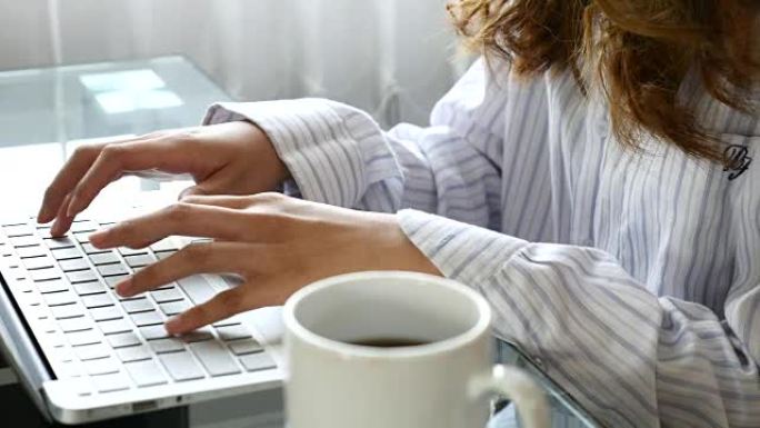 在带咖啡杯、电脑、4K(UHD) 的笔记本电脑上工作的女人