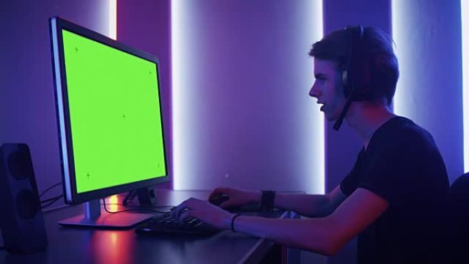 职业玩家的Arc Sholt在他的个人计算机上的绿色模拟屏幕上玩视频游戏。通过耳机上的麦克风与他的团
