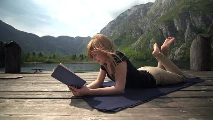 一个年轻的女人在山上的湖边看书