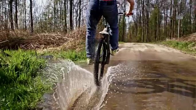 SLO MO下坡自行车手骑着自行车穿过水坑