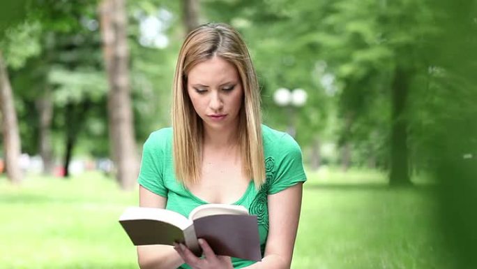 年轻女子在公园看书。