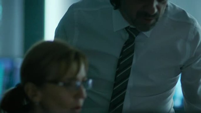 运营总监在个人计算机上工作时与女性IT专业人员交谈。慢动作。
