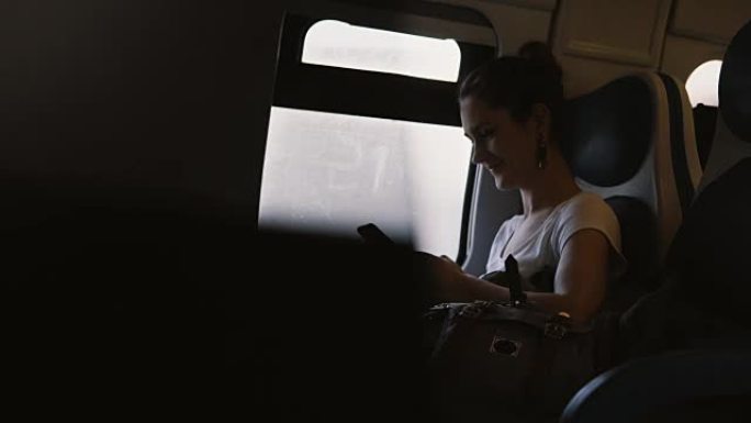 美丽微笑的欧洲女孩使用智能手机信使应用程序在火车上向朋友发送信息